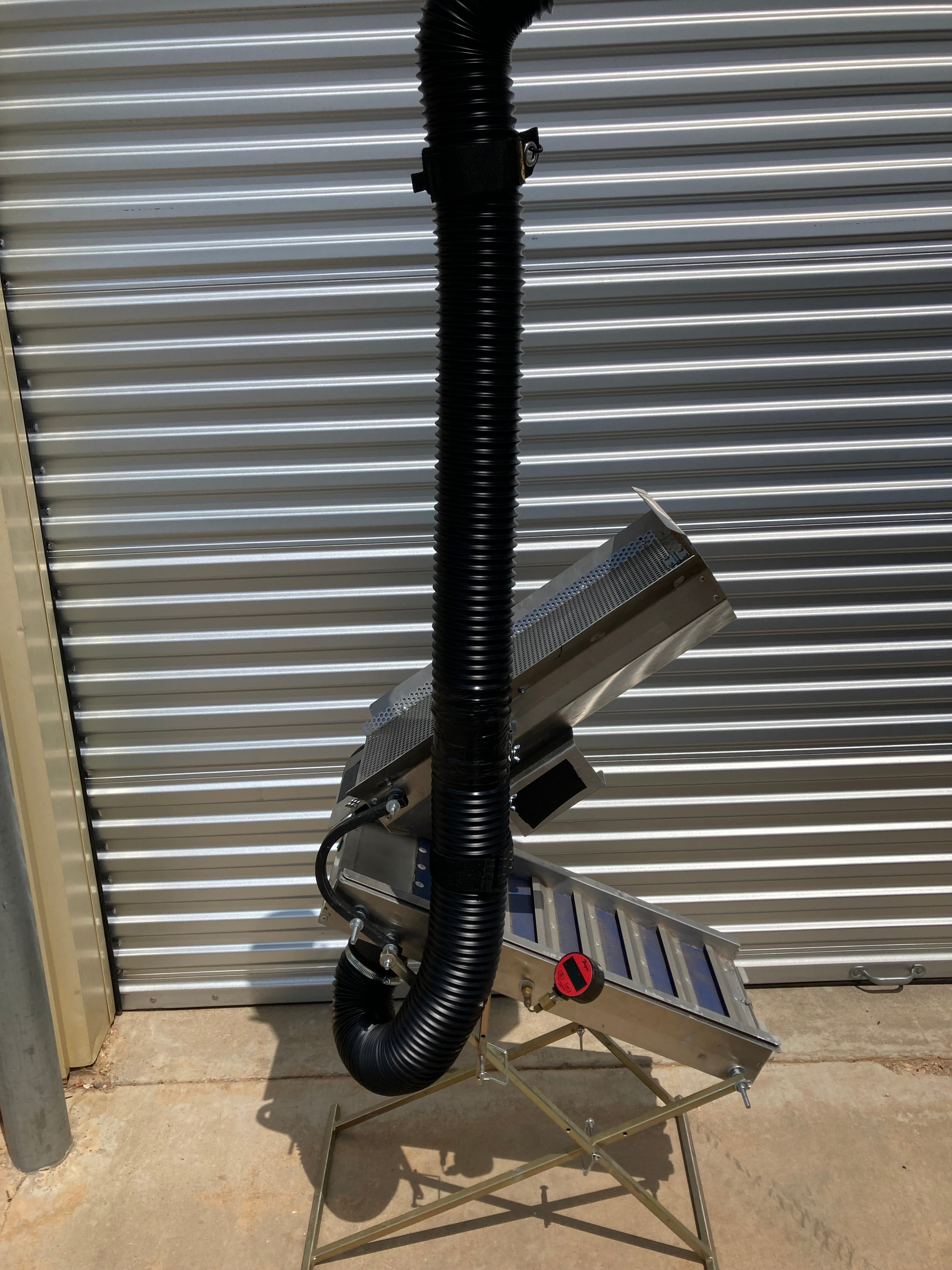 Full view of the Snorkel 12V Drywasher with the 4″ snorkel hose raised vertically ~6 ft, aluminum body, and tripod stand beside a corrugated wall.